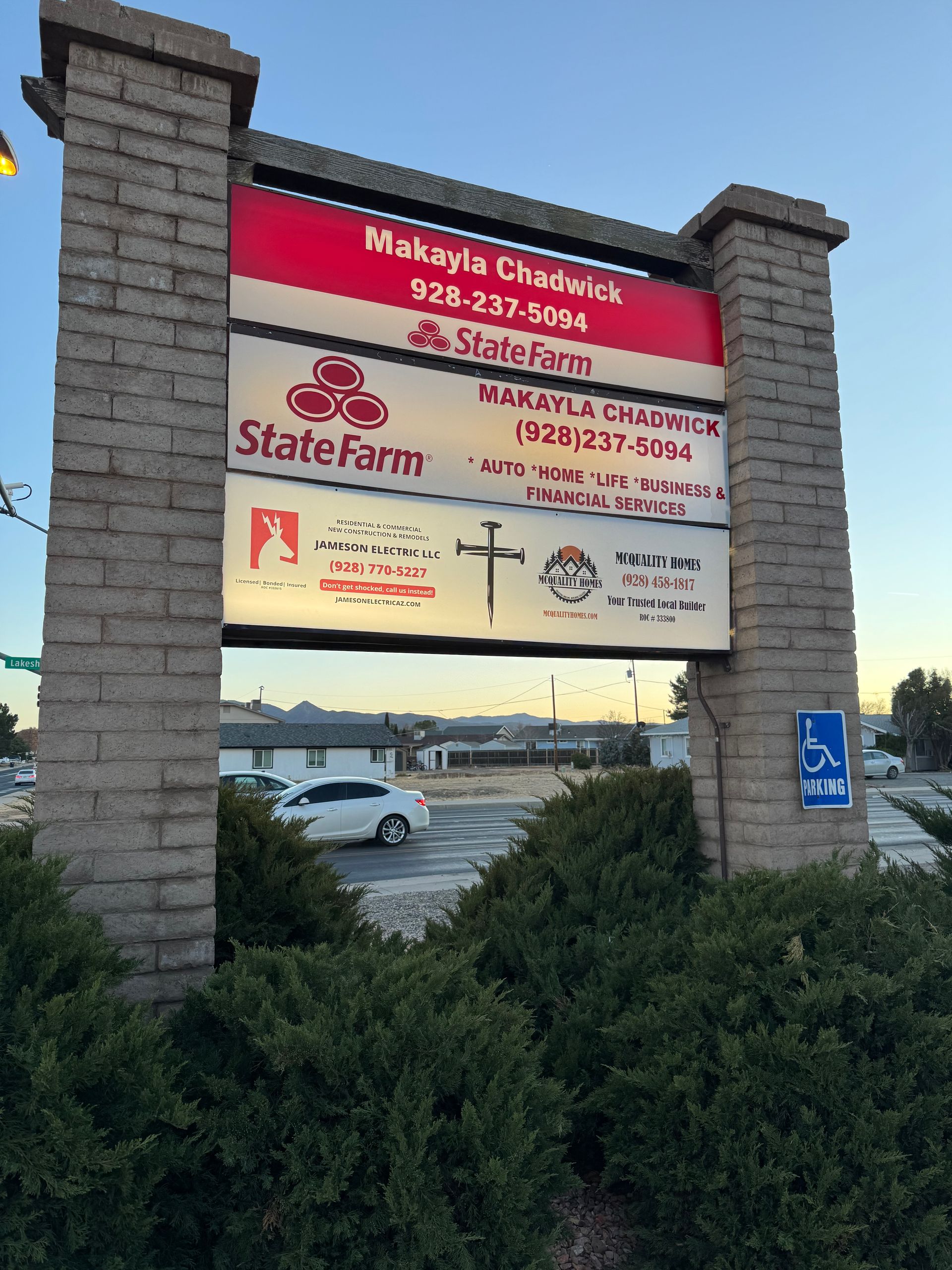 Sign for a building with multiple businesses, including State Farm. Brick columns, red and white signs.
