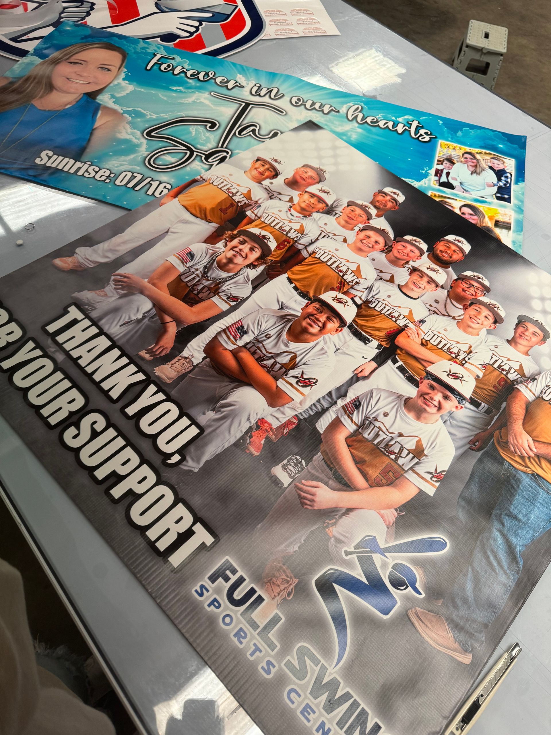 Posters thanking supporters, one with a group of baseball players and another with a photo of a young woman.