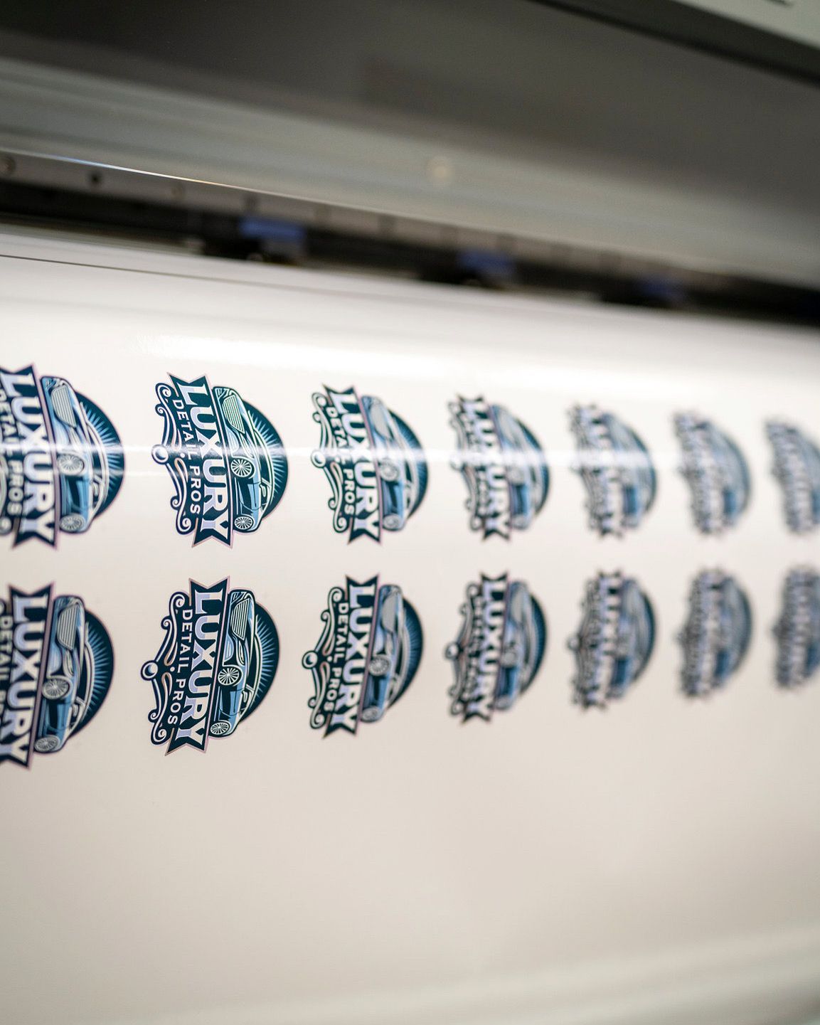 Labels with a blue and white logo are being printed on a roll of white paper by a machine.
