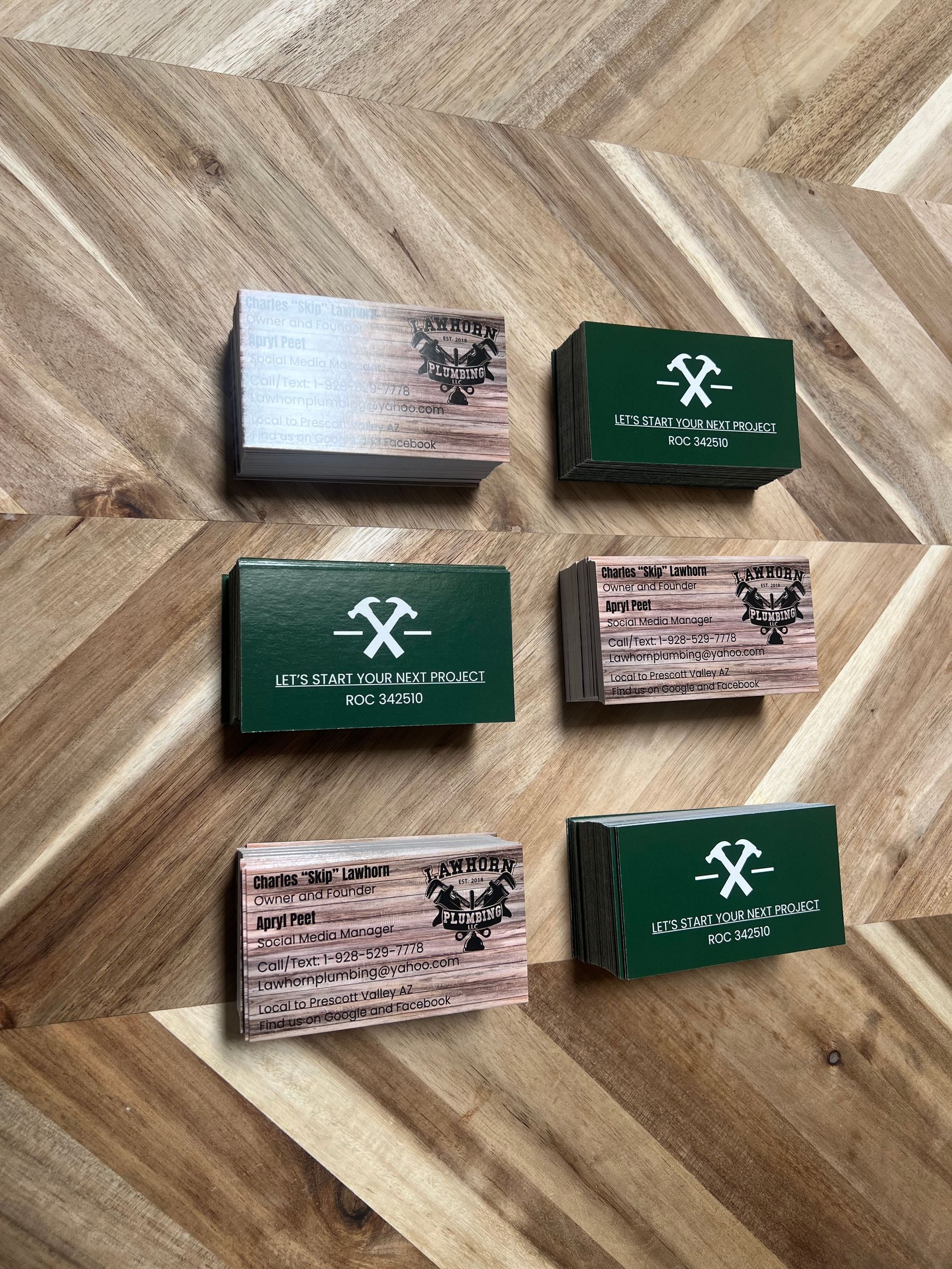Six small boxes with wood-grain and green exteriors, some with a logo of a hammer and text, arranged on a wooden surface.