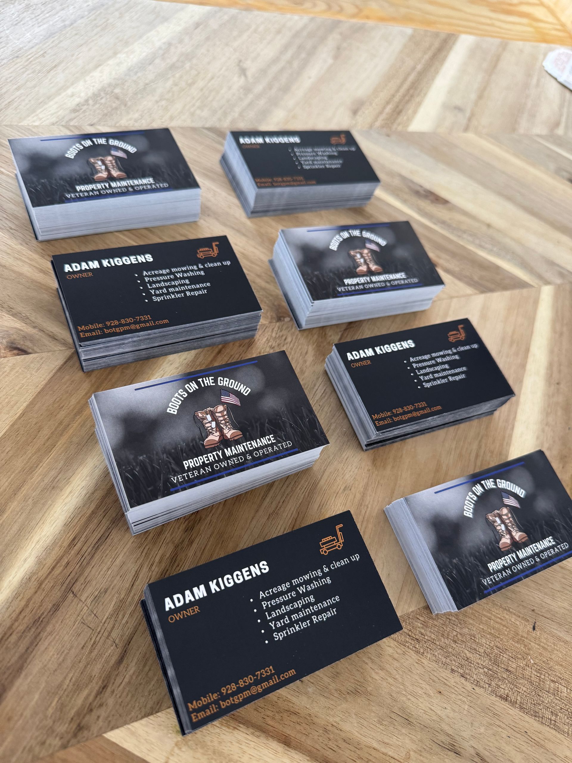 Stacks of business cards with the name Adam Higgins and a logo, on a wooden surface.