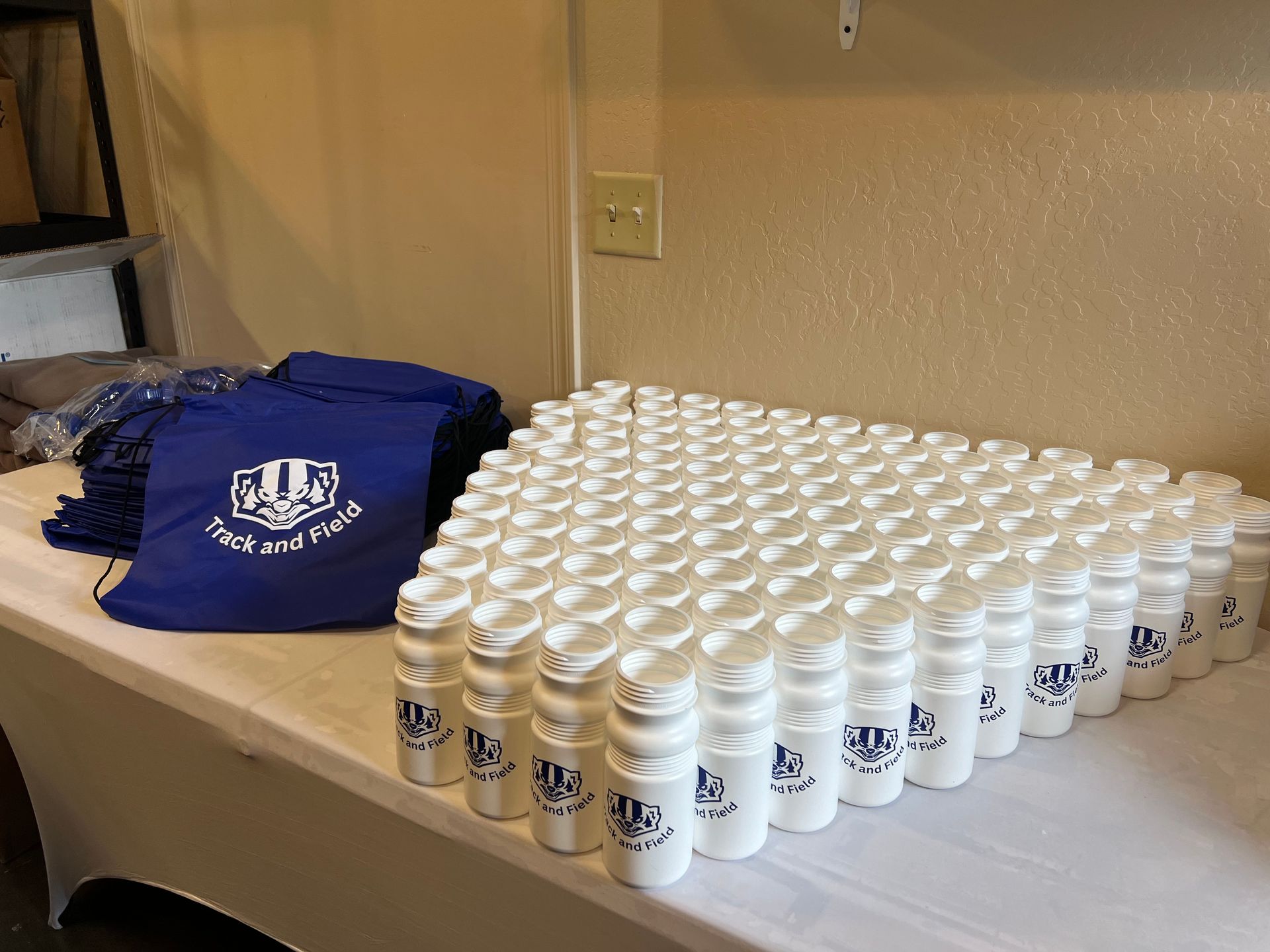 White pill bottles and blue drawstring bags on a table, likely for a promotional event.
