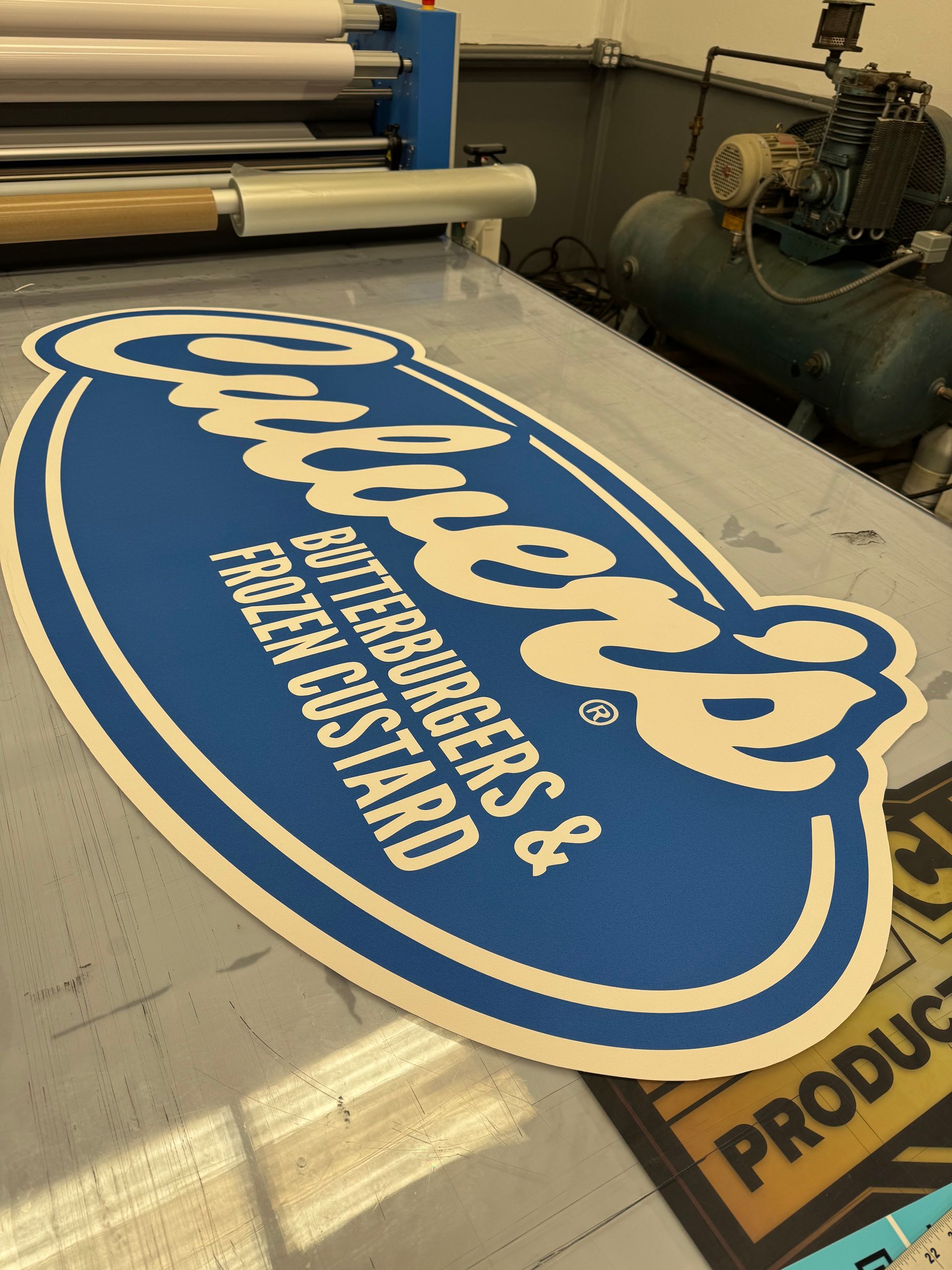 Large sign for Culver's butterburgers & frozen custard, blue and white, on a printing machine.