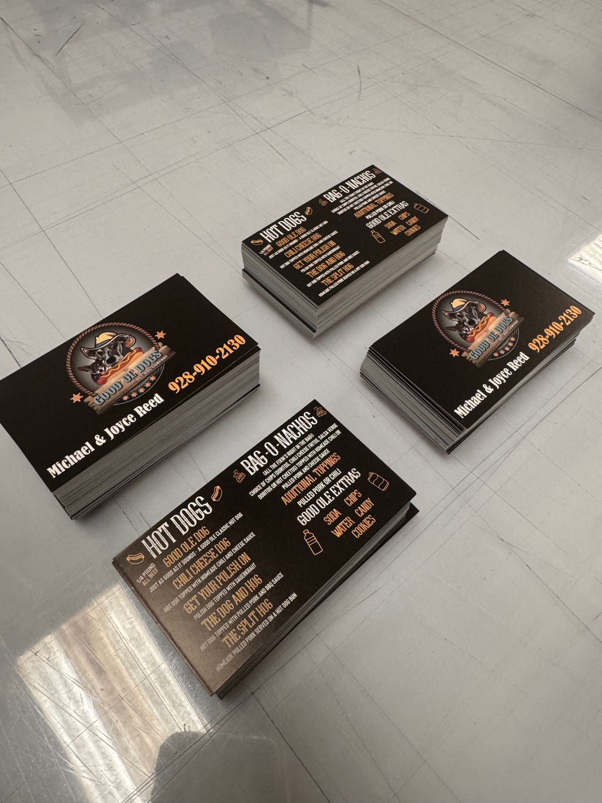 Four stacks of business cards with black background, logo, and text on a white surface.