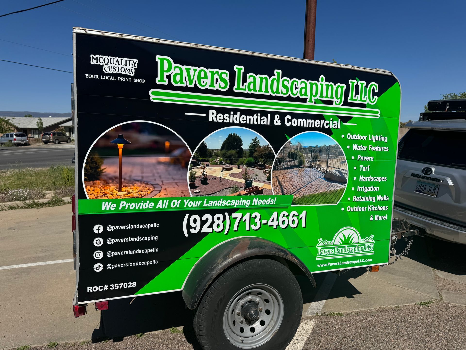 Black trailer with Pavers Landscaping LLC logo, phone number, and landscaping photo examples.
