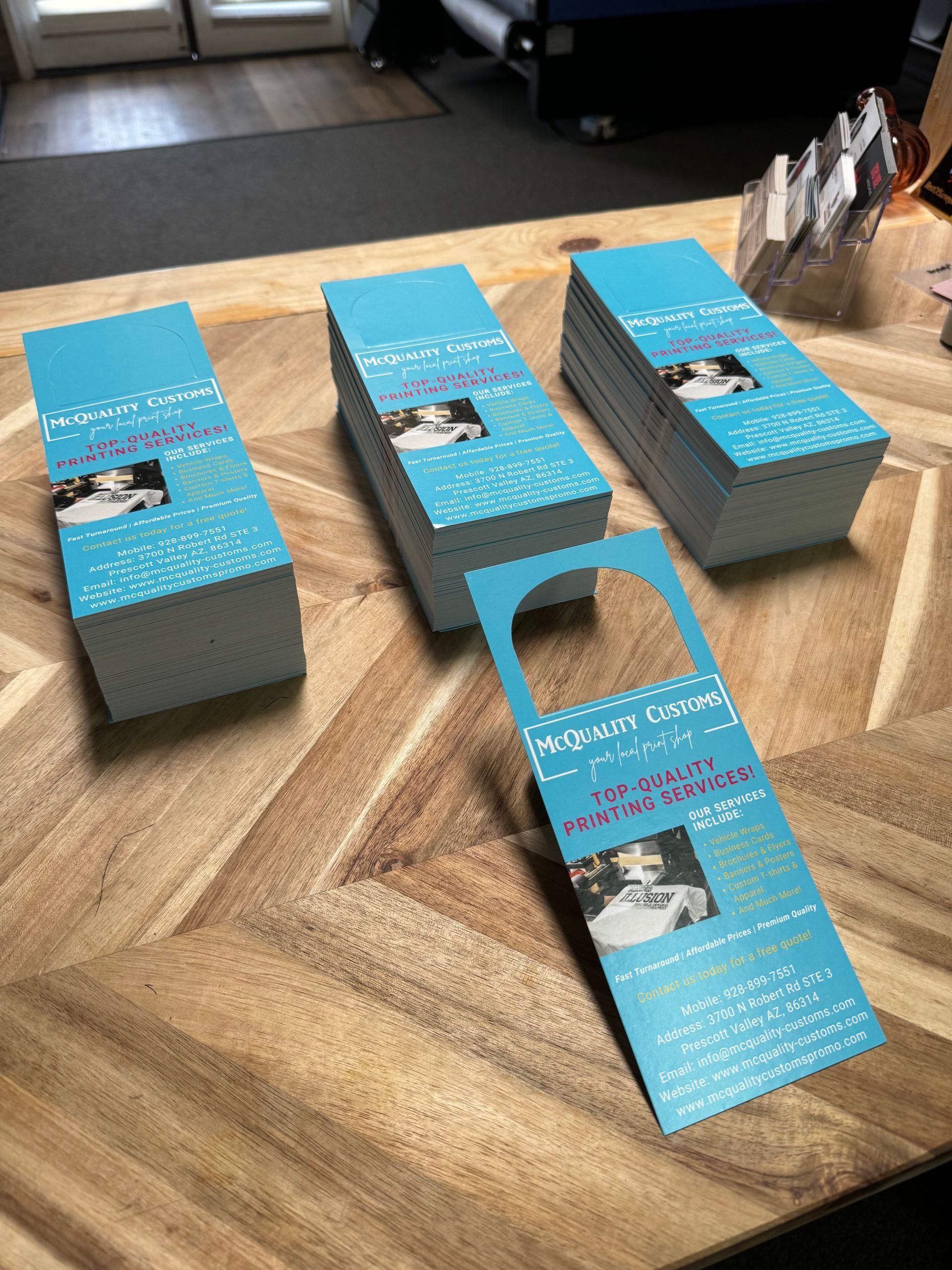 Stacks of blue door hangers with a woman's picture on a wooden table.