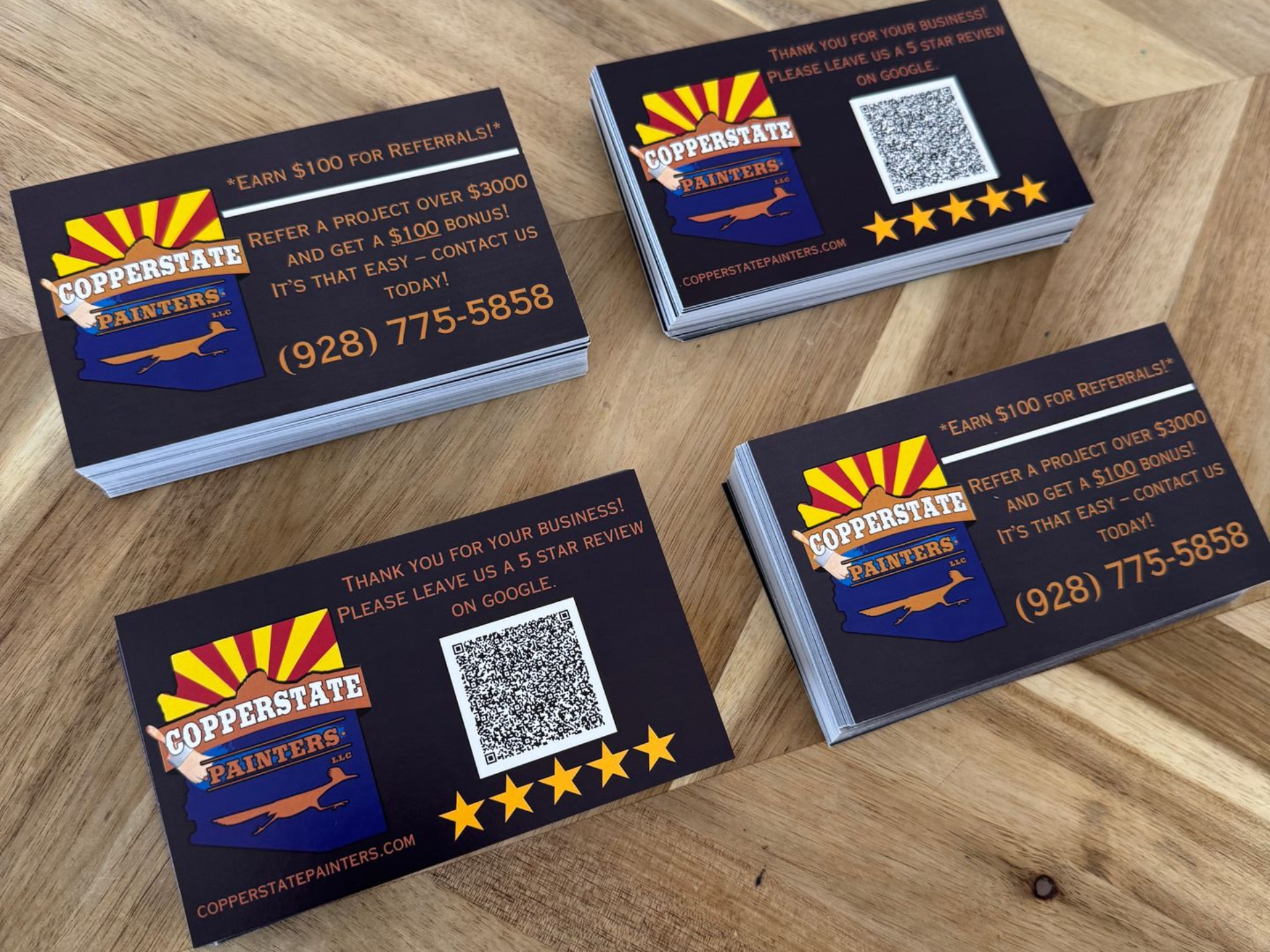 Business cards with logo, Arizona outline, and discount offer, stacked on a wooden surface.