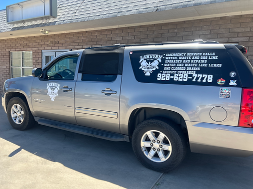 Silver SUV with logo and phone number on the side, parked in front of a building.
