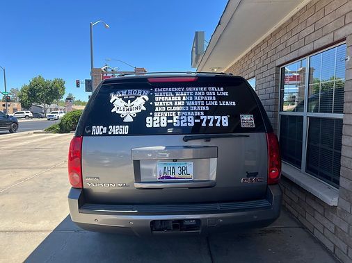 Gray SUV with white text on back window, parked near building. Arizona license plate.