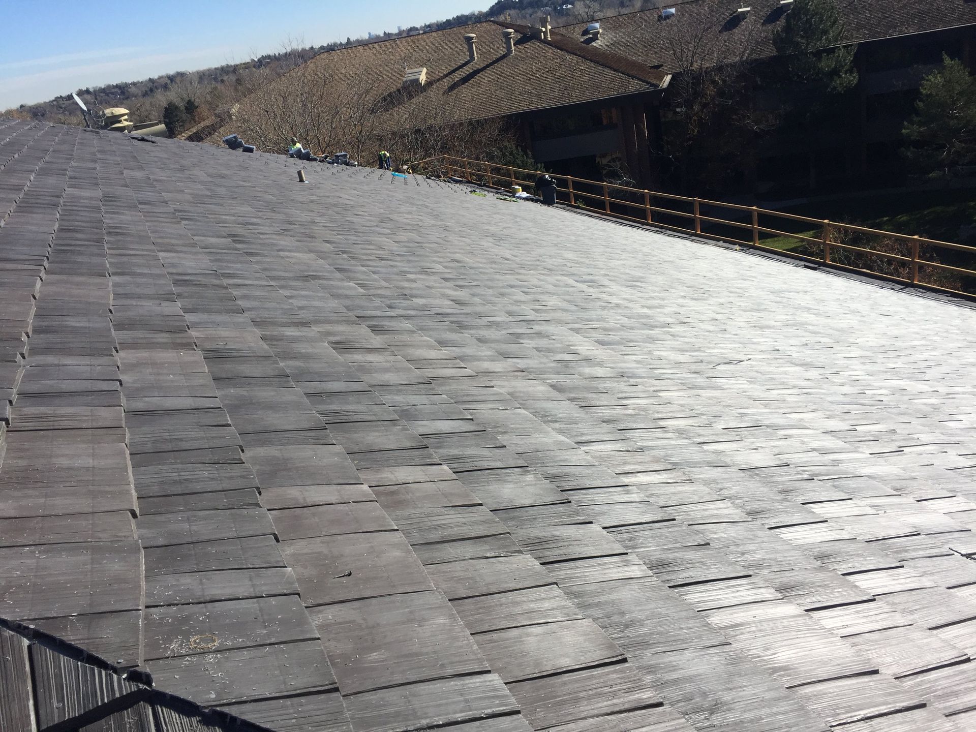 A dark grey tiled roof on a sunny day.
