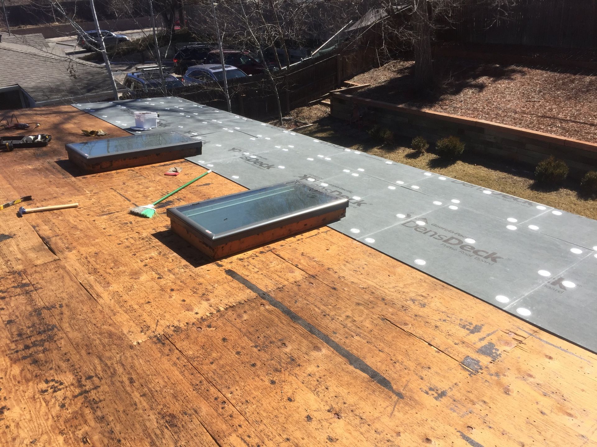 Rooftop with two skylights, gray underlayment, and exposed wood.