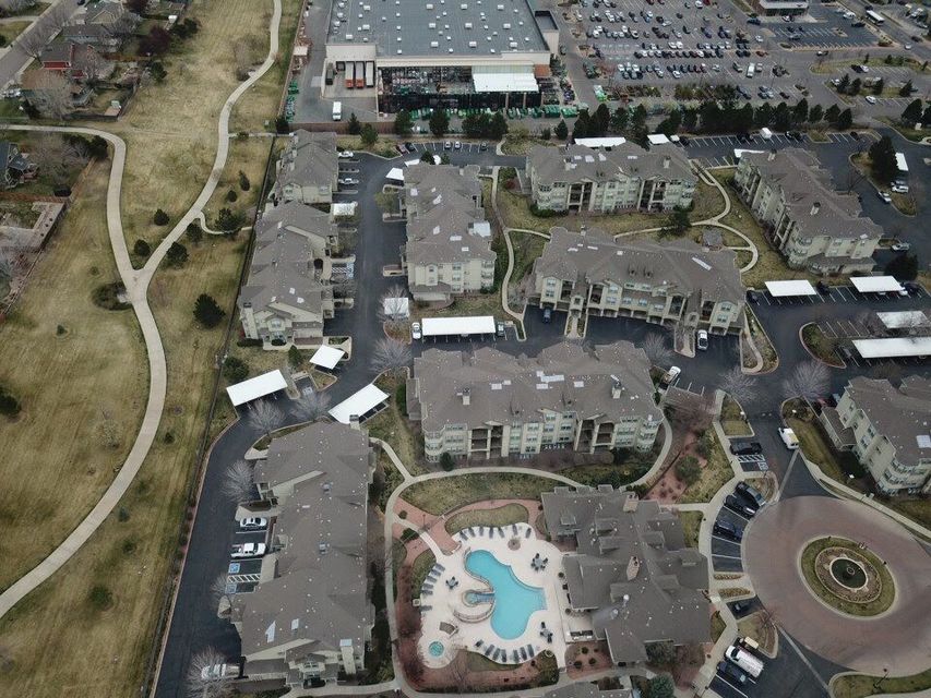 Aerial view of an apartment complex with a pool, parking lots, and a large retail store in the background.