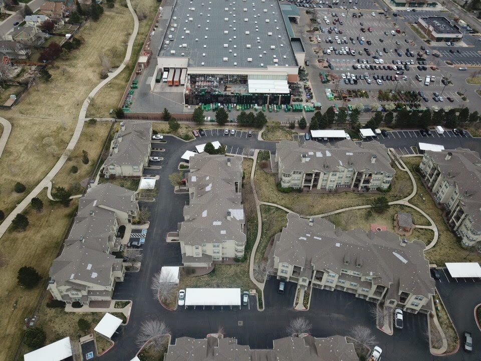 Aerial view of apartment buildings near a large warehouse and parking lot.