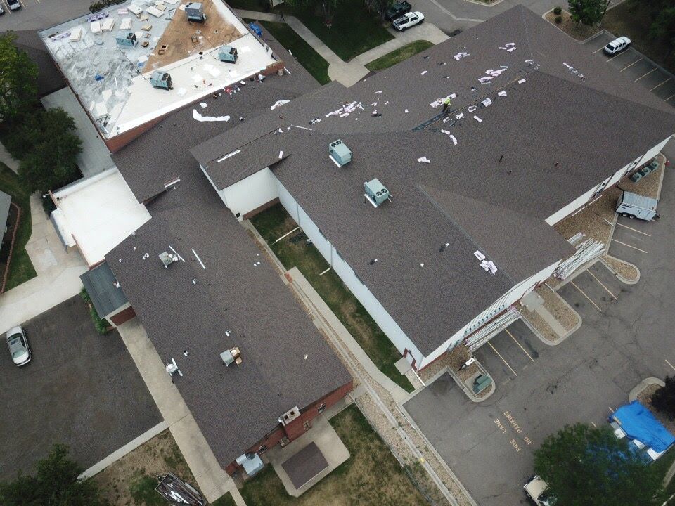 Aerial view of a brown-roofed building with various sections and cars parked around it.