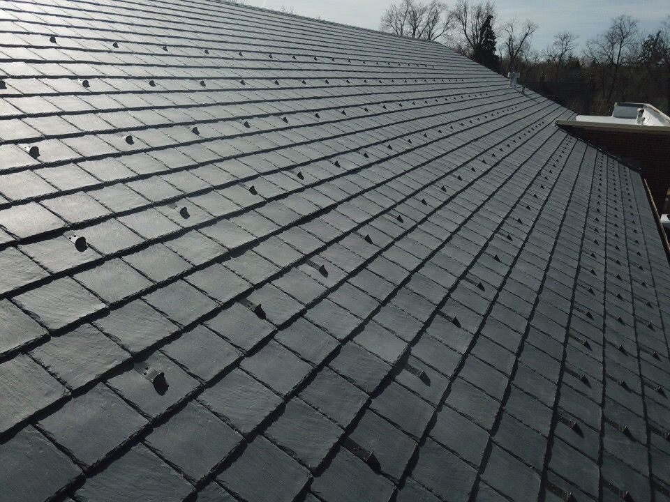 Gray tiled roof with numerous dark colored, round, protruding fasteners.