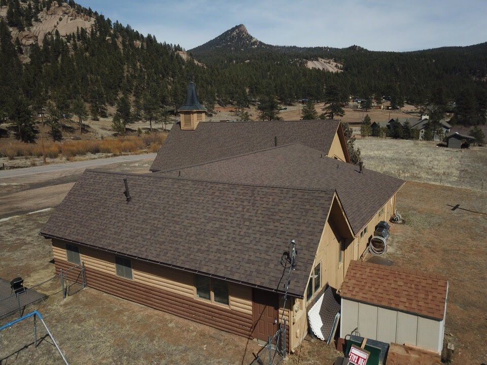 Brown-roofed building in a mountain setting; a peak in the background.
