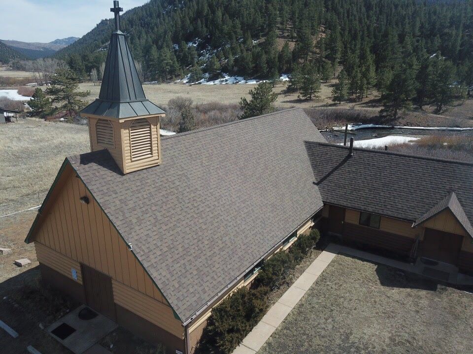 Church with steeple in a valley, surrounded by trees and a river.