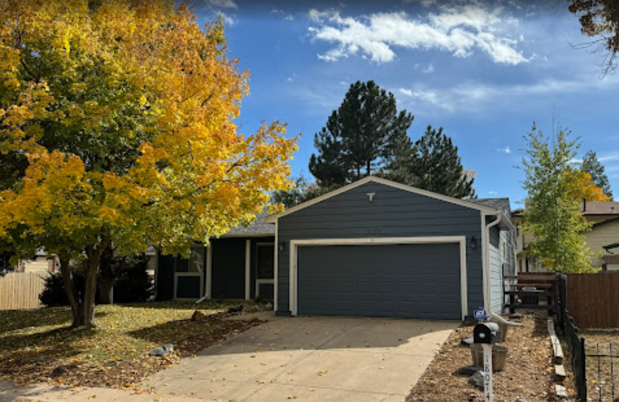 Spacious foyer with a curved staircase, wood floors, and a rug; an open view of a living room.