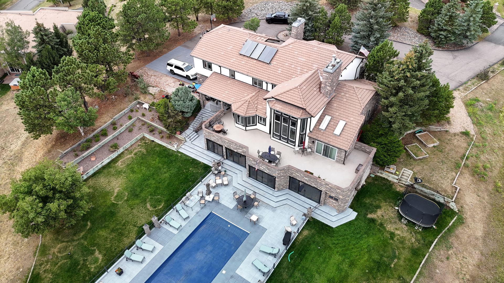 Aerial view of a large, modern house with a pool, patio, and green lawn.