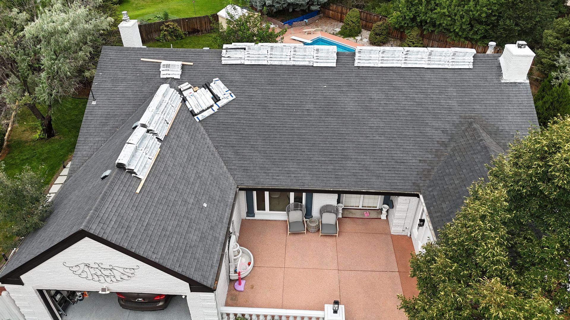 Overhead view of a white house with a dark roof and a patio area.