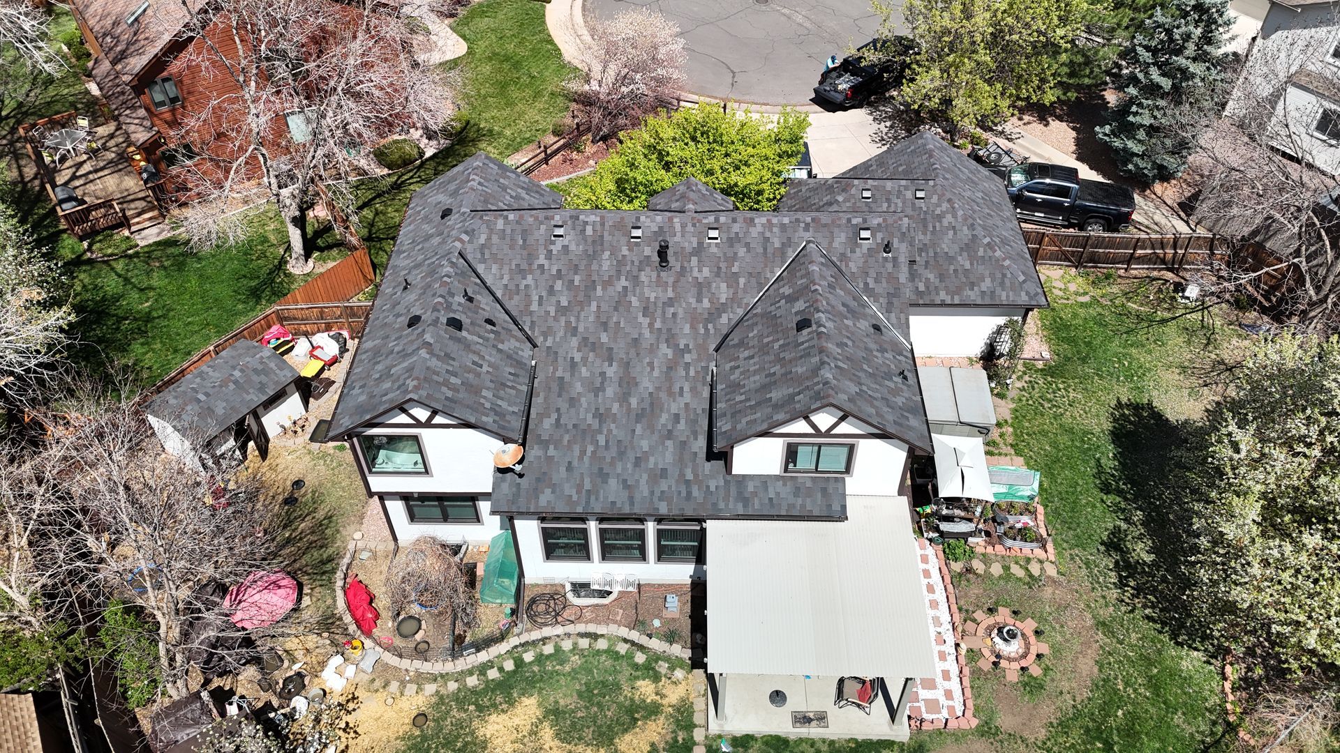 Aerial view of a Tudor-style house with a gray roof, white walls, and a grassy yard.
