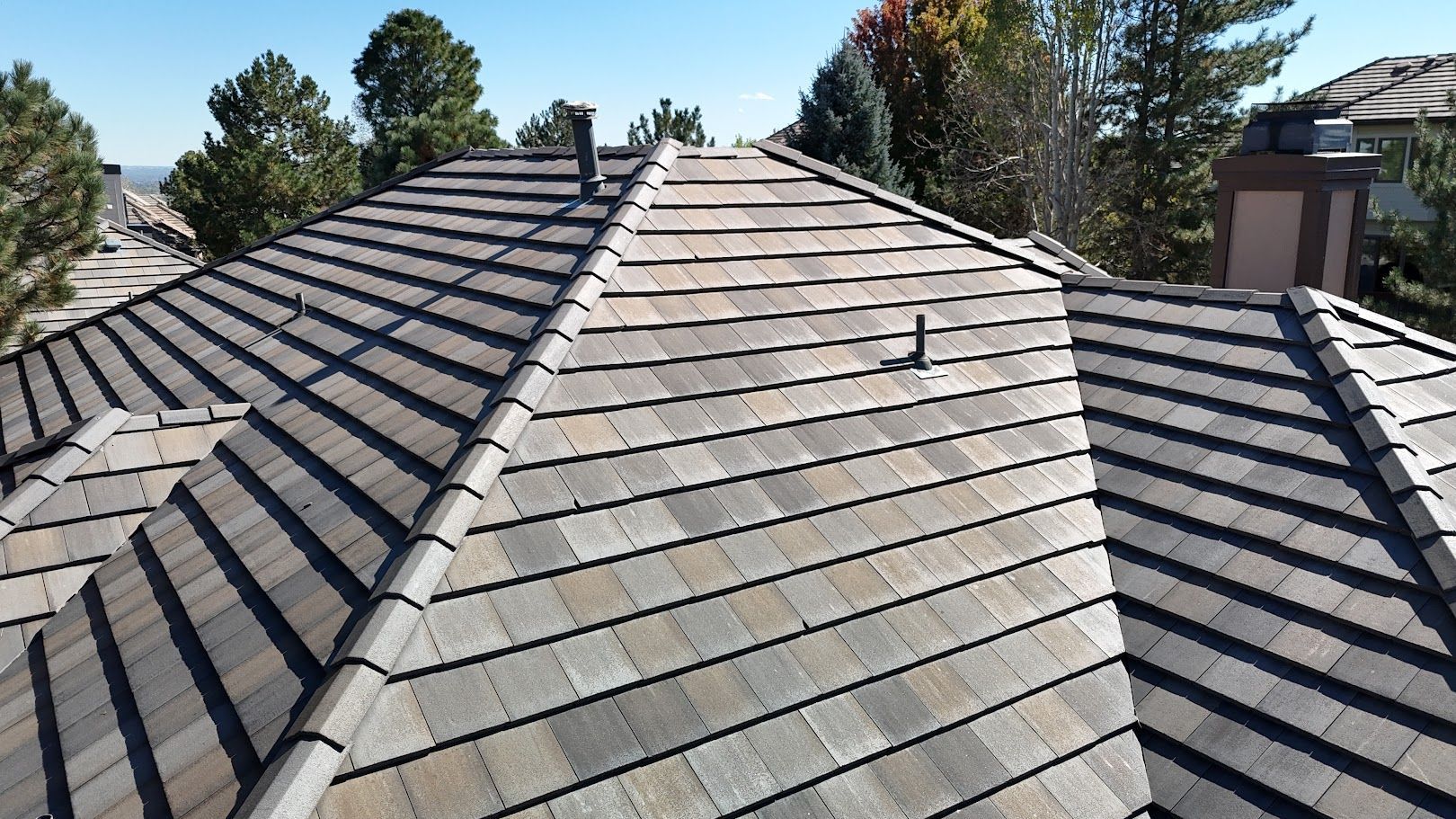 Slate-tiled residential roof with skylight vents, viewed from above under a clear sky