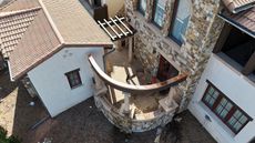 Two-story house with a ladder on the roof under an overcast sky.