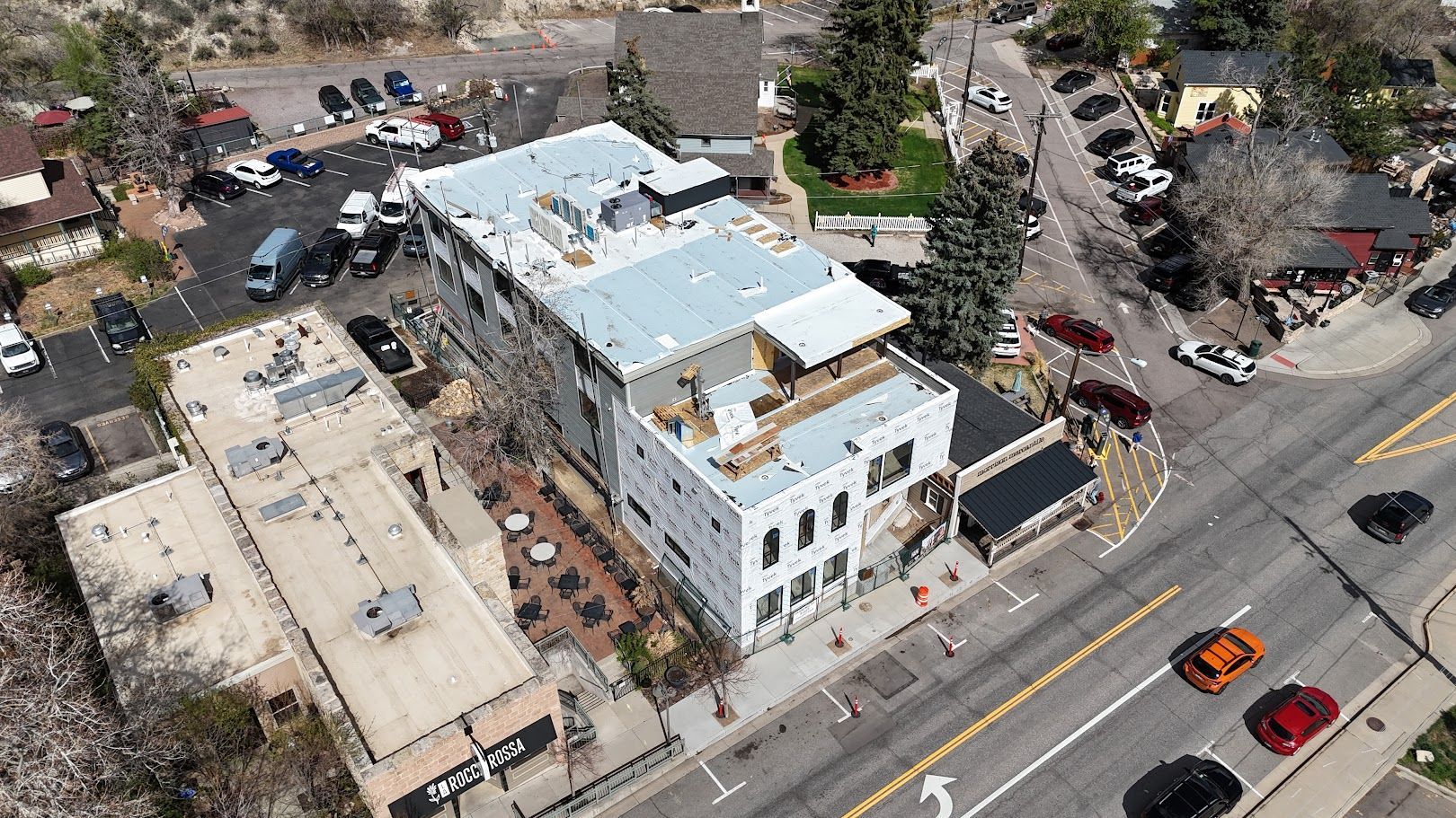 A wide, flat white commercial roof under a bright blue sky with scattered clouds and several HVAC units.
