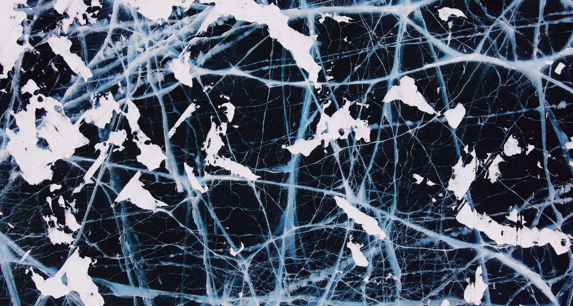 Spacious foyer with a curved staircase, wood floors, and a rug; an open view of a living room.