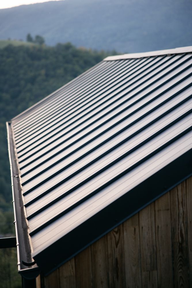Spacious foyer with a curved staircase, wood floors, and a rug; an open view of a living room.