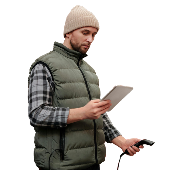 A man wearing a vest and a beanie is using a tablet