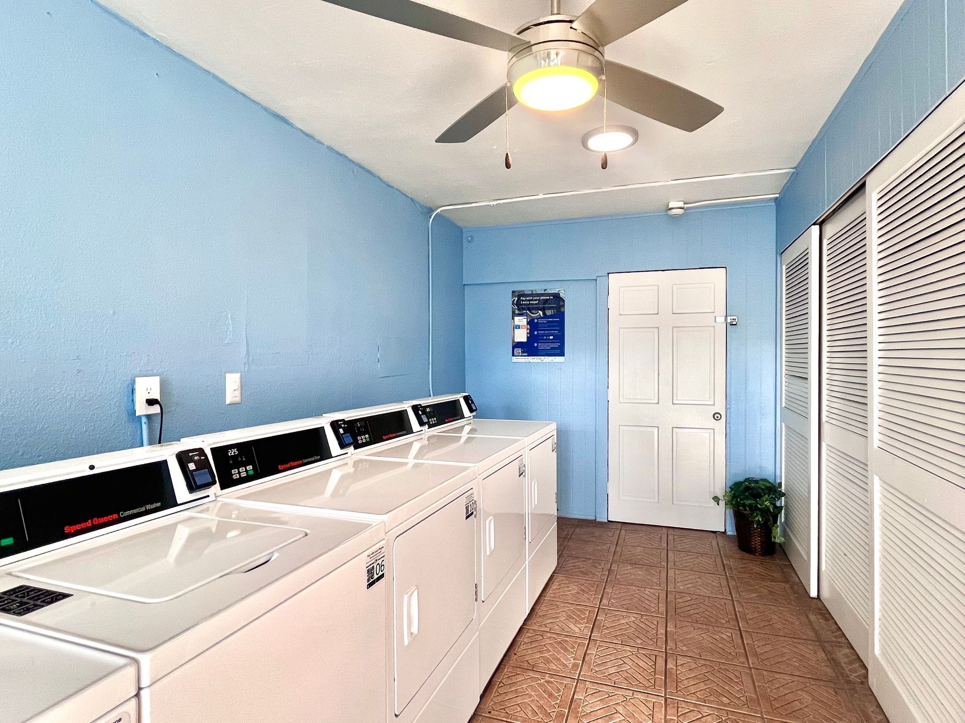 Laundry room with white washers/dryers, blue walls, a white door, and a ceiling fan.