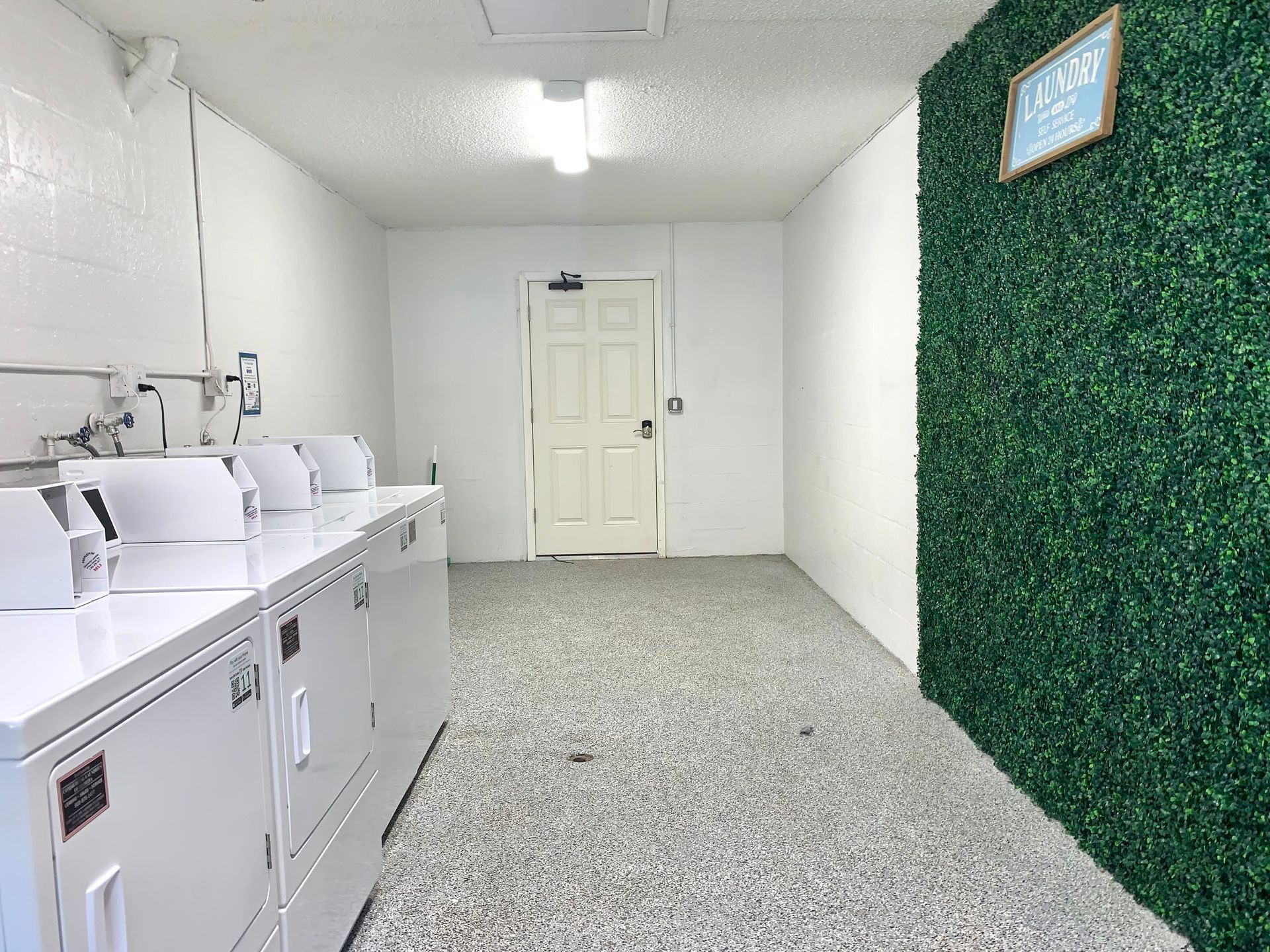 A laundry room with white machines, a door, and a green wall.