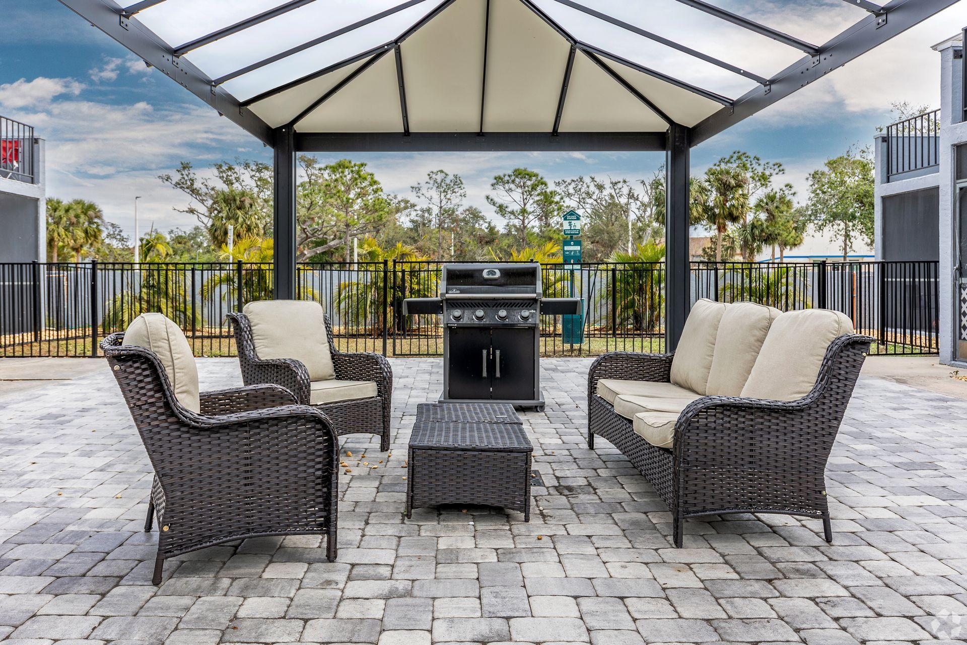 Outdoor lounge area with wicker furniture, grill, and gazebo.