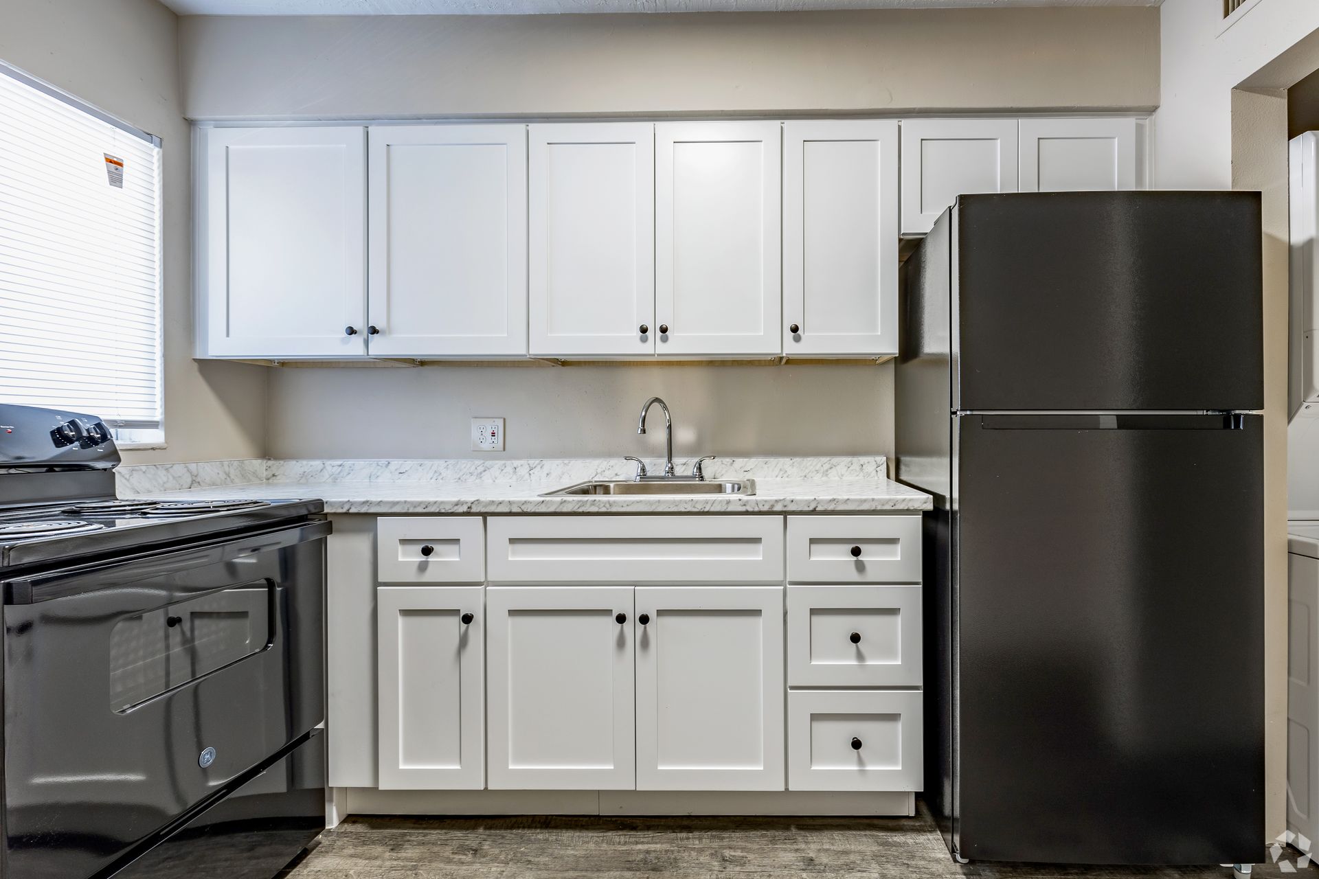 White kitchen with stainless steel appliances and gray countertops.