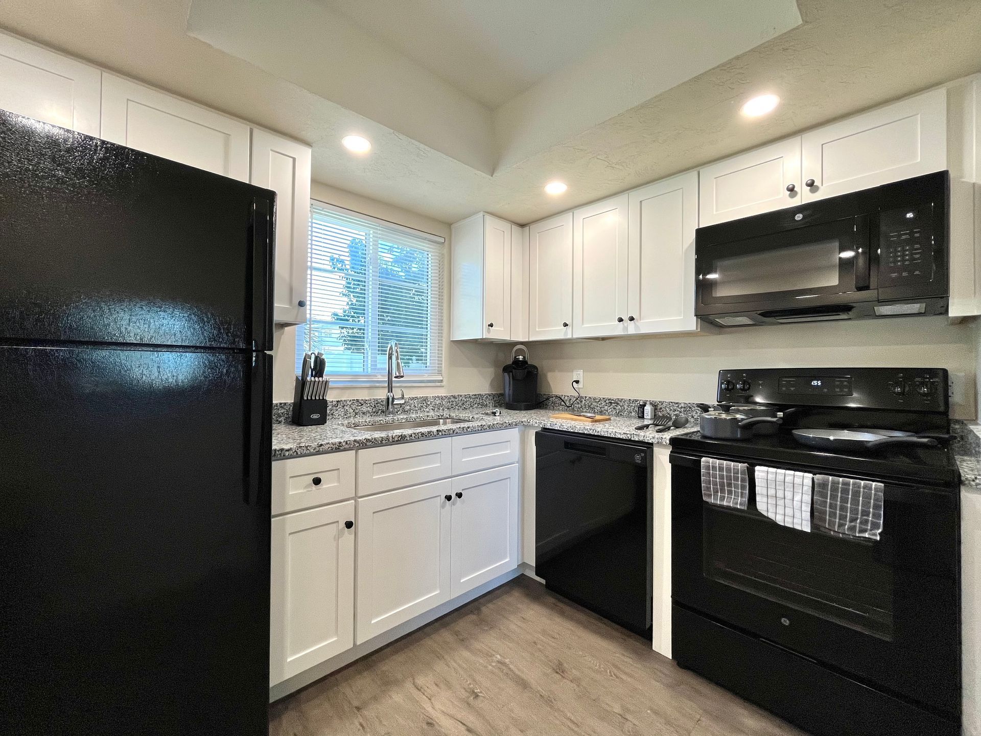 White kitchen with black appliances and granite countertops.