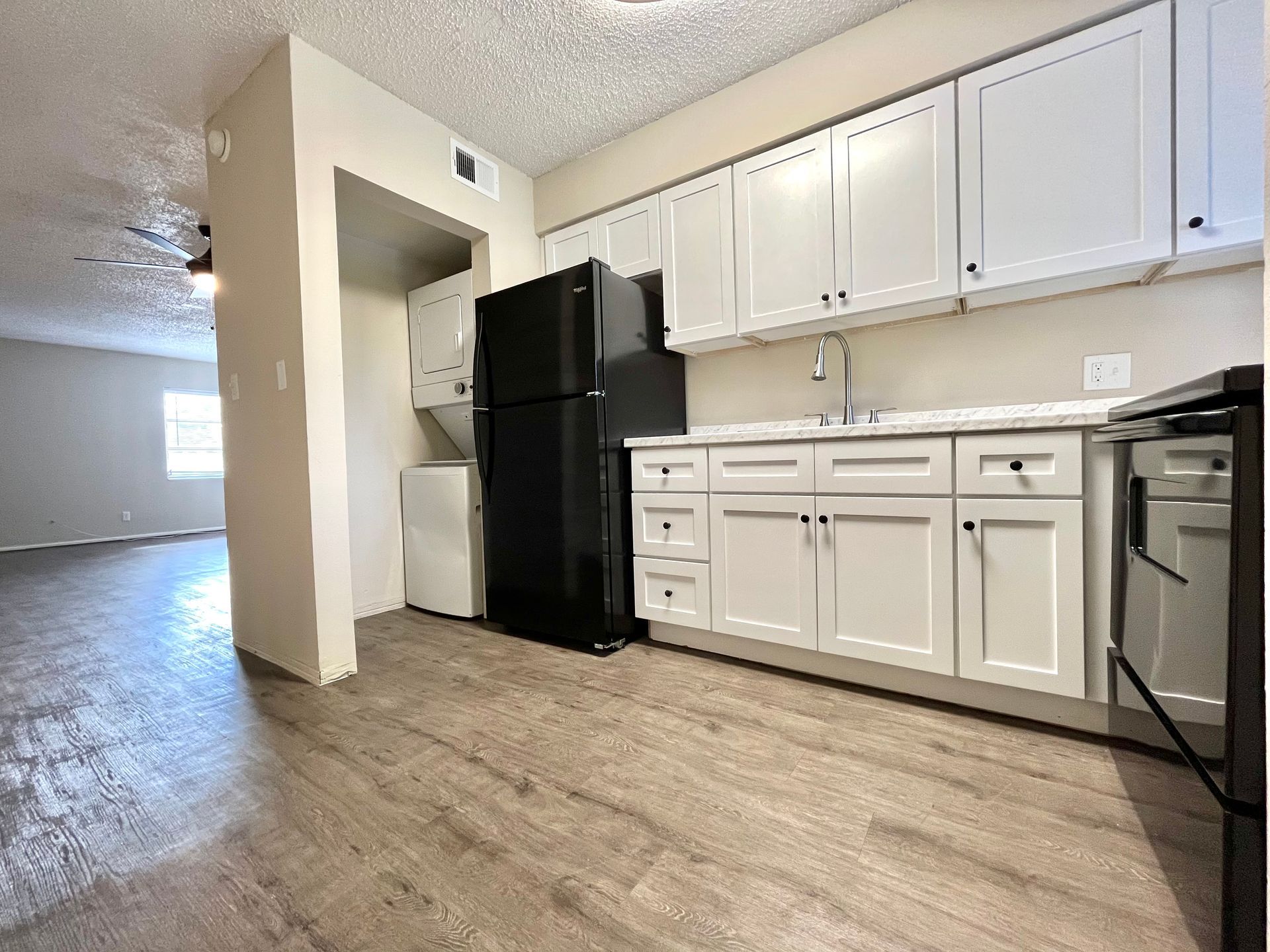 Kitchen with white cabinets, black appliances, and light wood floors.