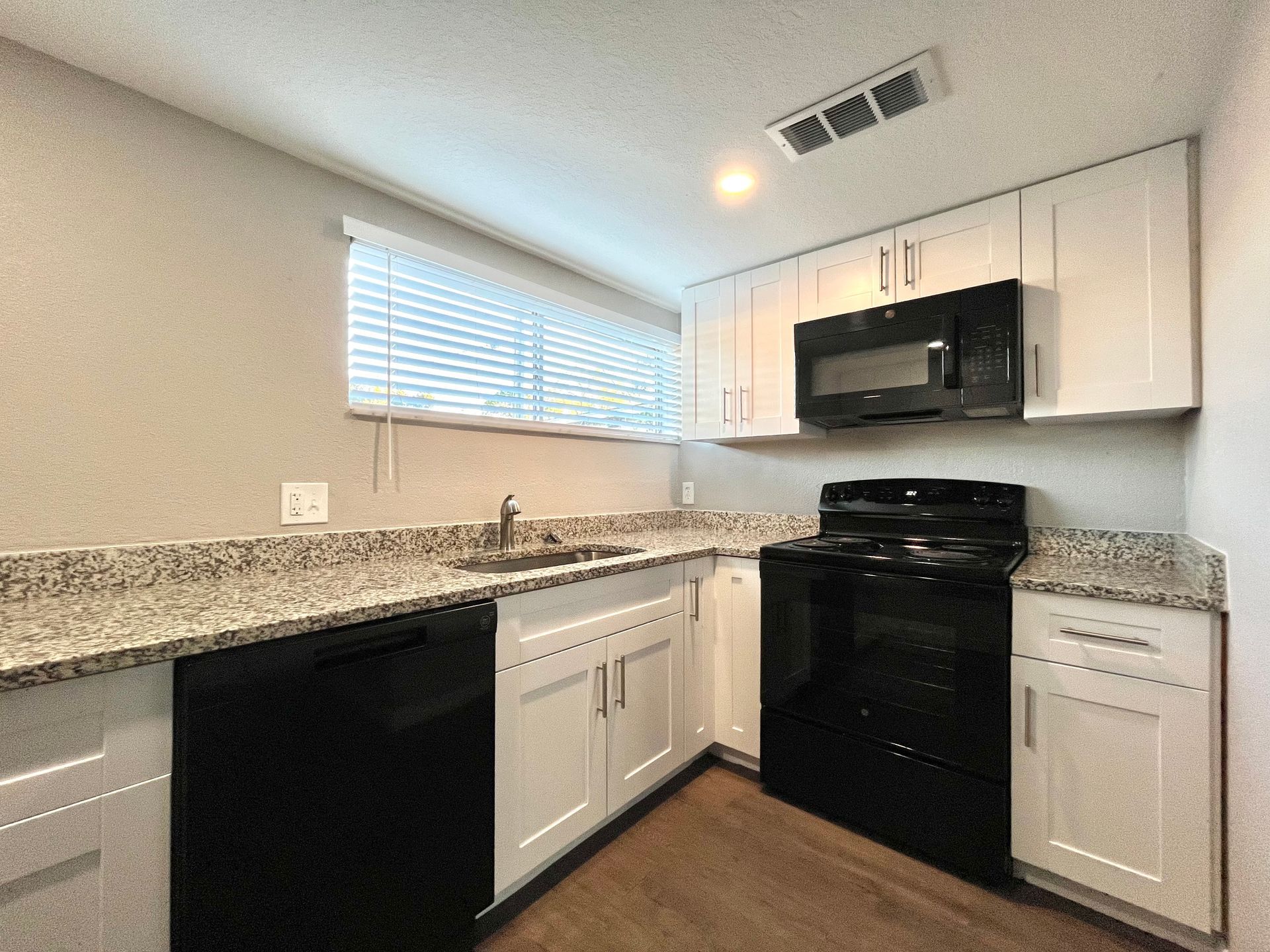 Kitchen with white cabinets, black appliances, and granite countertops.