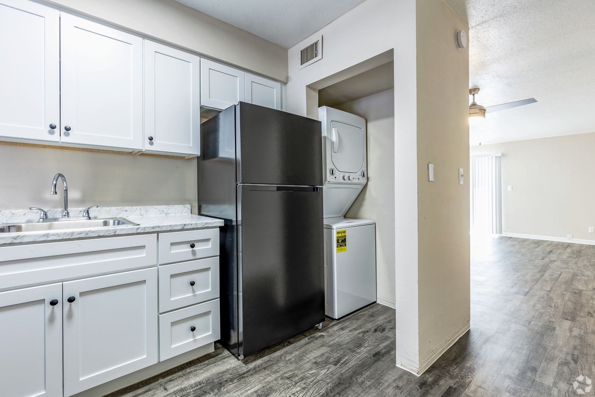 Kitchen with white cabinets, black refrigerator, and a stacked washer/dryer.