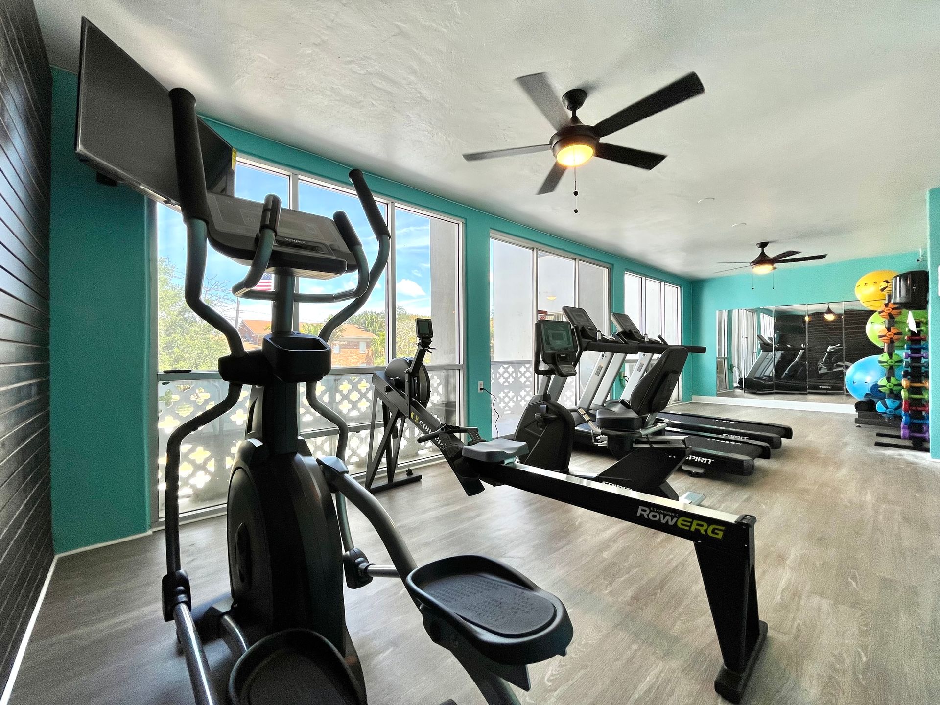 Gym with elliptical, treadmills, weights, and turquoise walls.