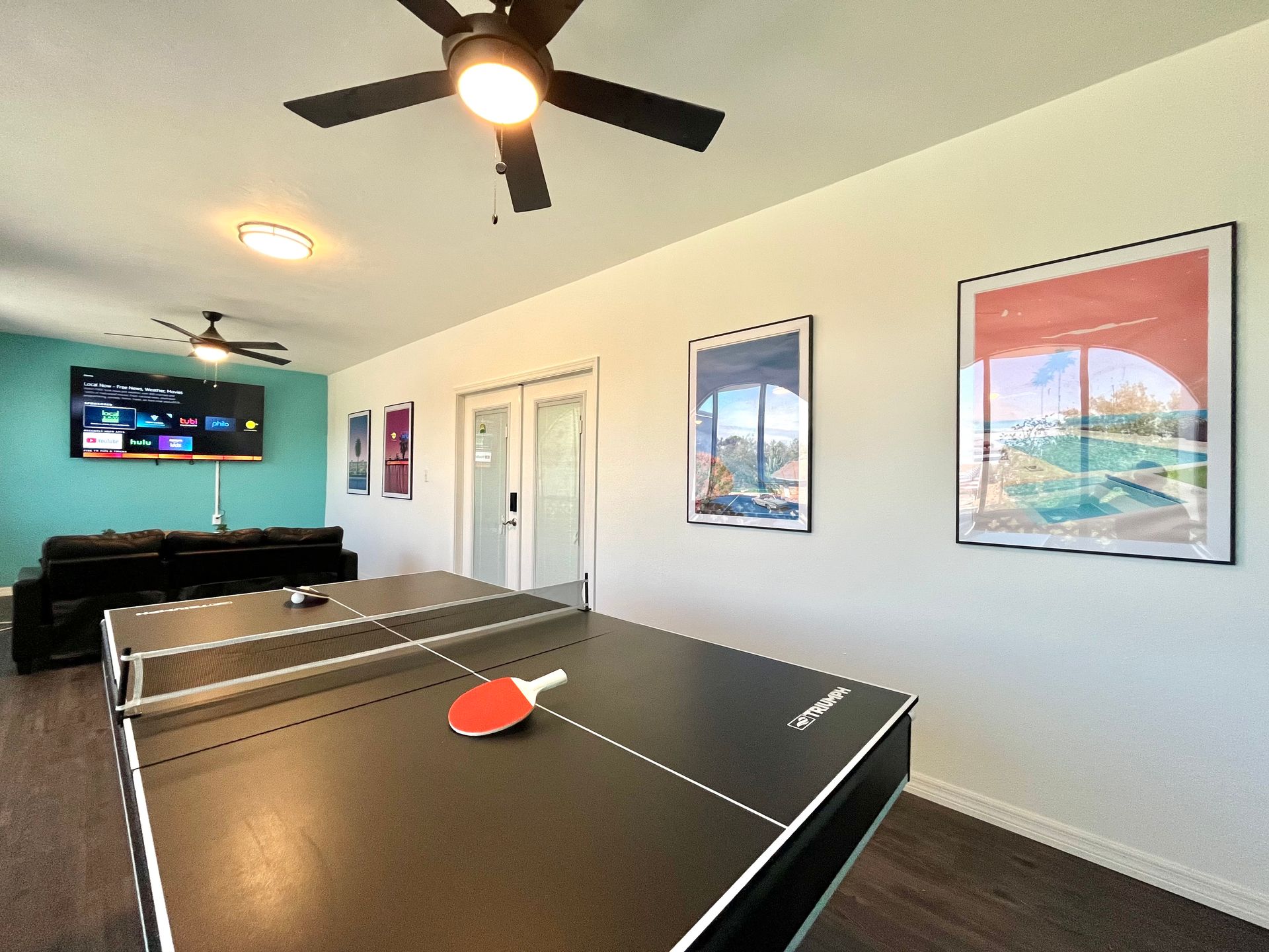 Ping pong table in a game room with posters and a TV.