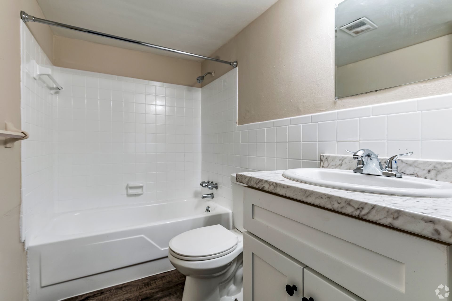 A small, white bathroom with a toilet, sink, and shower/tub combo.