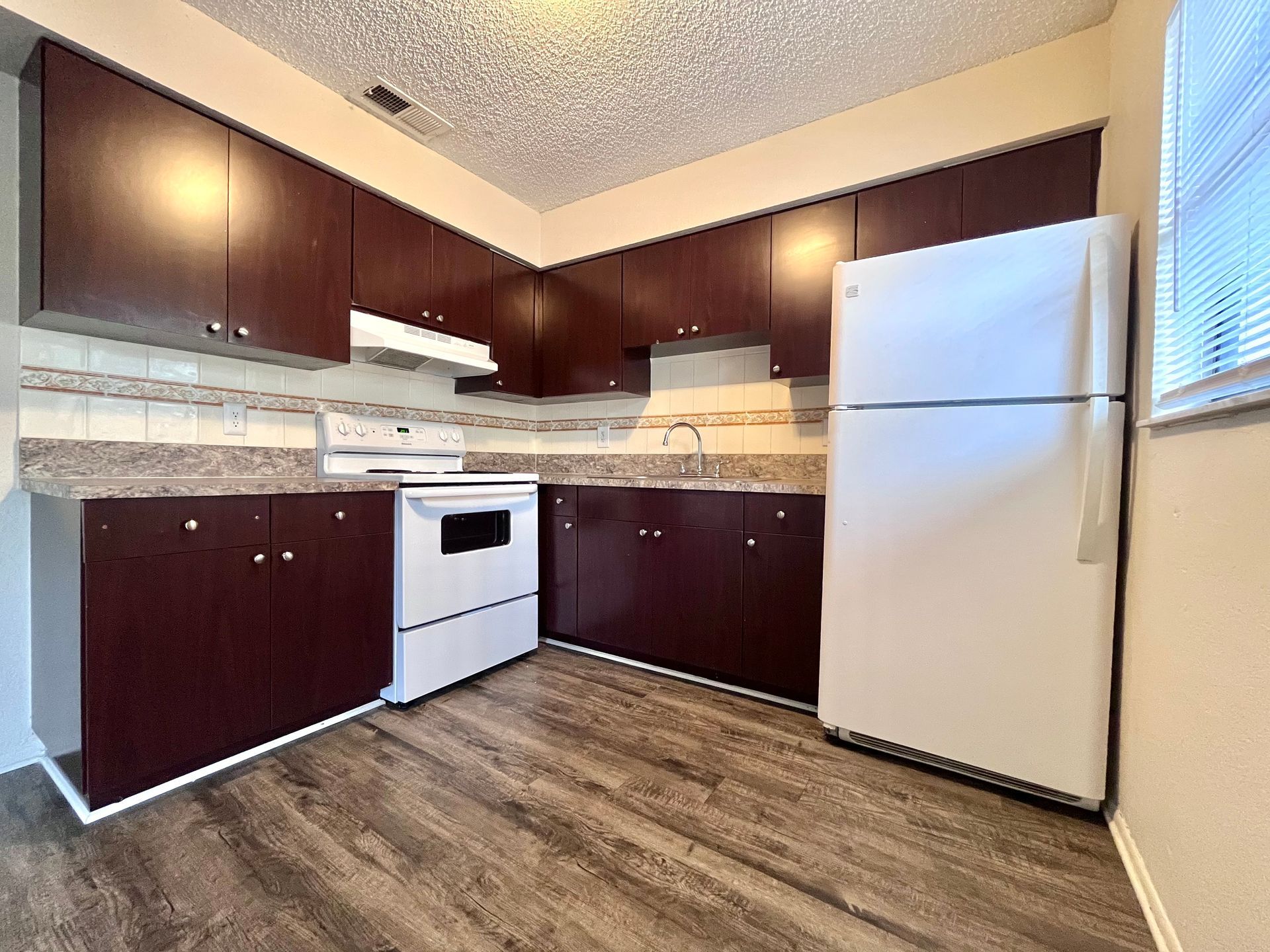 Kitchen with wood cabinets, black appliances, and light-colored flooring.