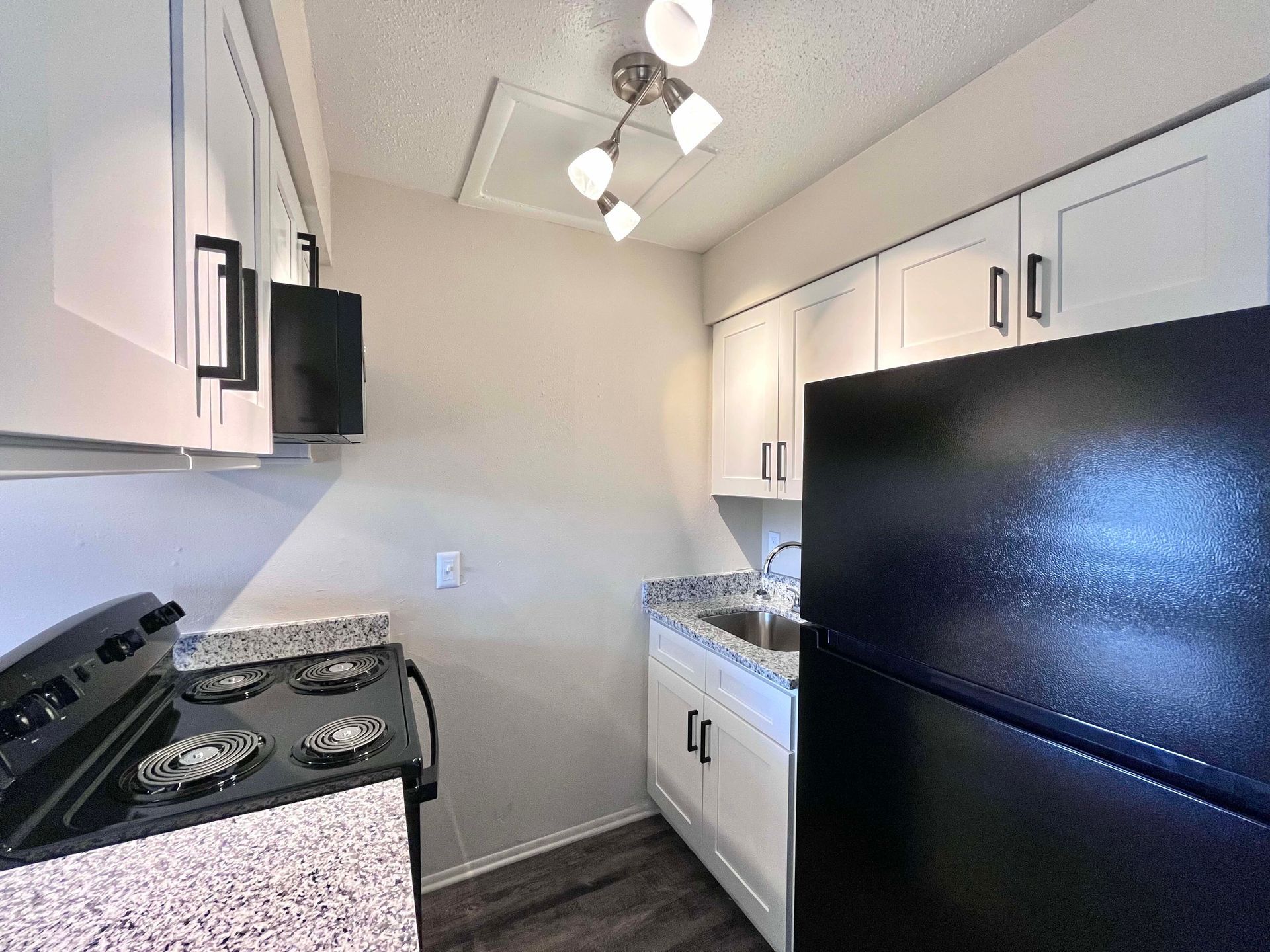 Small kitchen with white cabinets, black appliances, and granite countertops.
