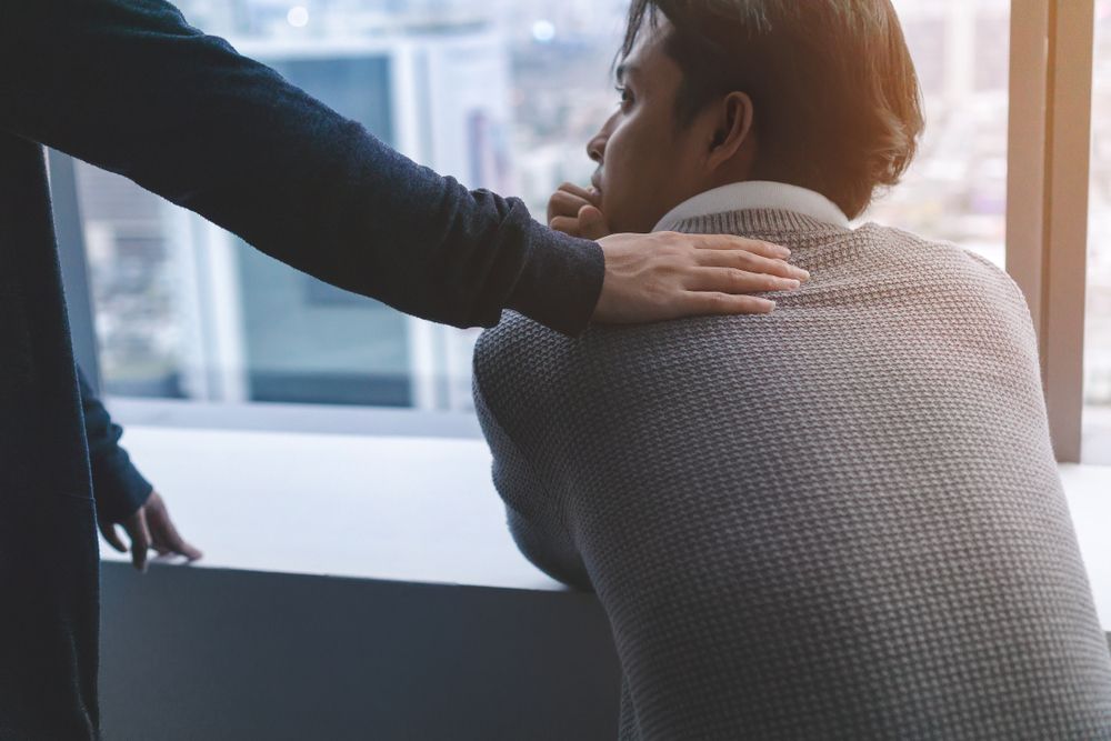 A Man Is Being Comforted By Another Man While Looking Out Of A Window — Psych Solutions NT in Darwin, NT