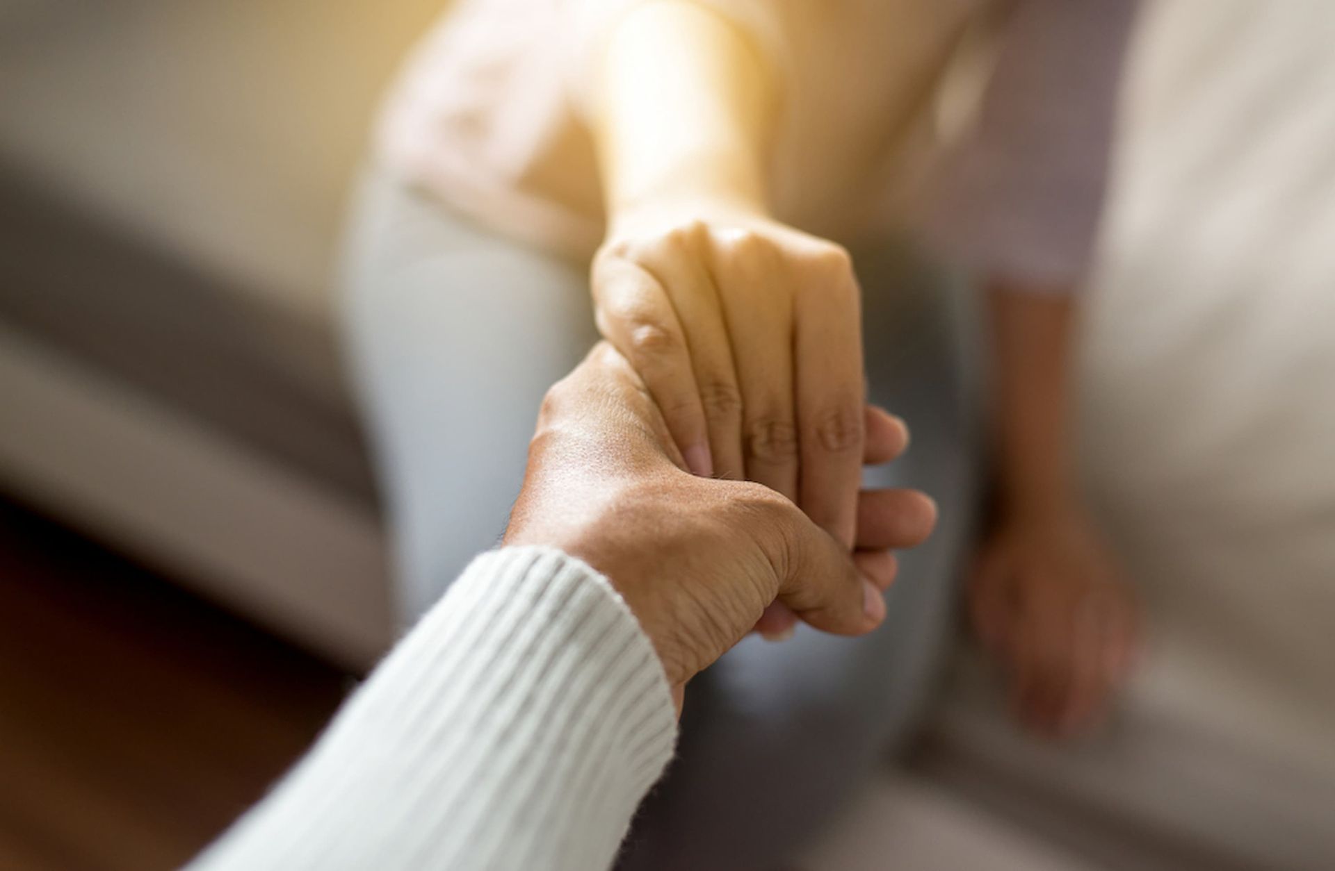 A Person Is Holding Another Person's Hand While Sitting on A Couch — Psych Solutions NT in Darwin, NT