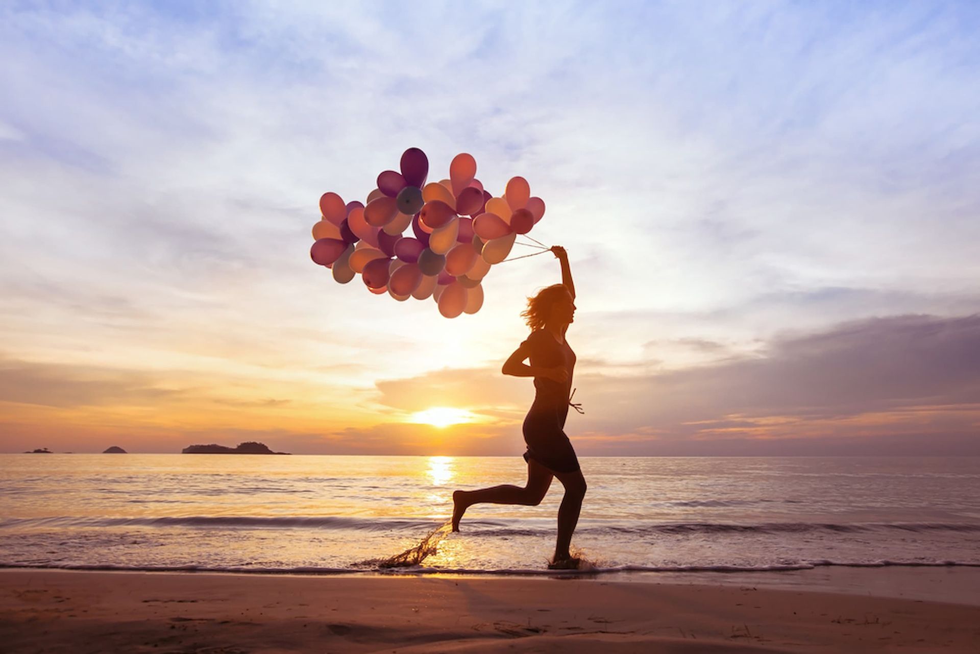 A Woman Is Running on The Beach Holding a Bunch of Balloons — Psych Solutions NT in Leanyer, NT