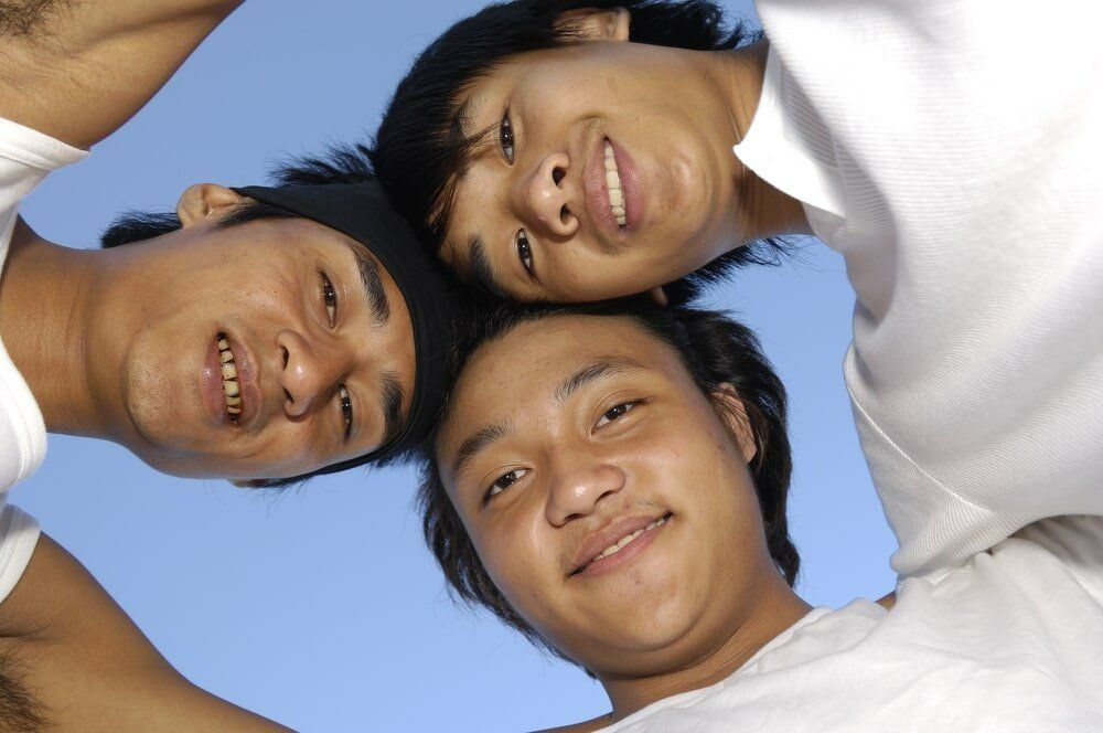 Three Young Men Are Huddled Together and Smiling for The Camera — Psych Solutions NT in Leanyer, NT