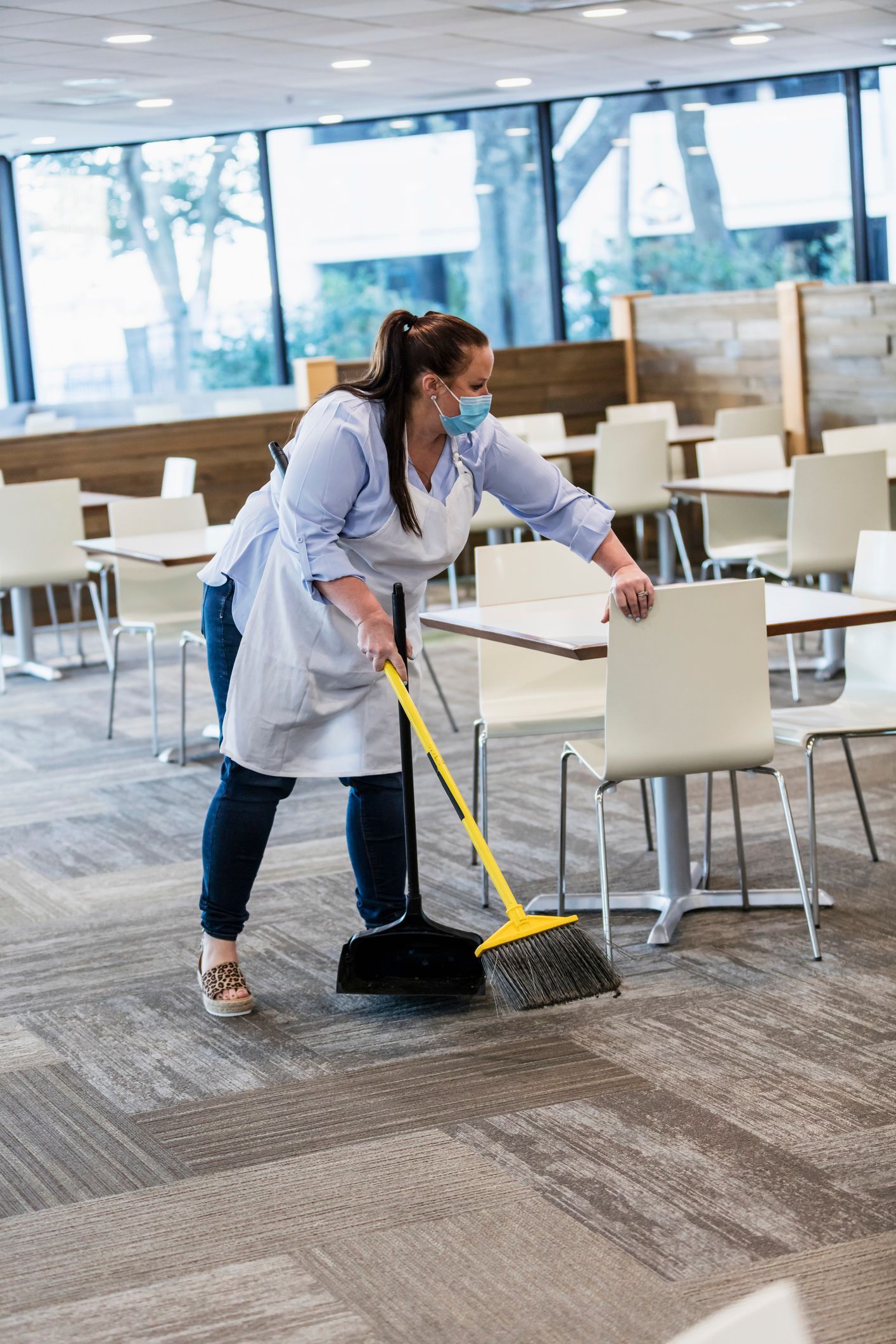 Carrello per le pulizie con prodotti in un centro commerciale, accanto a una scala mobile.