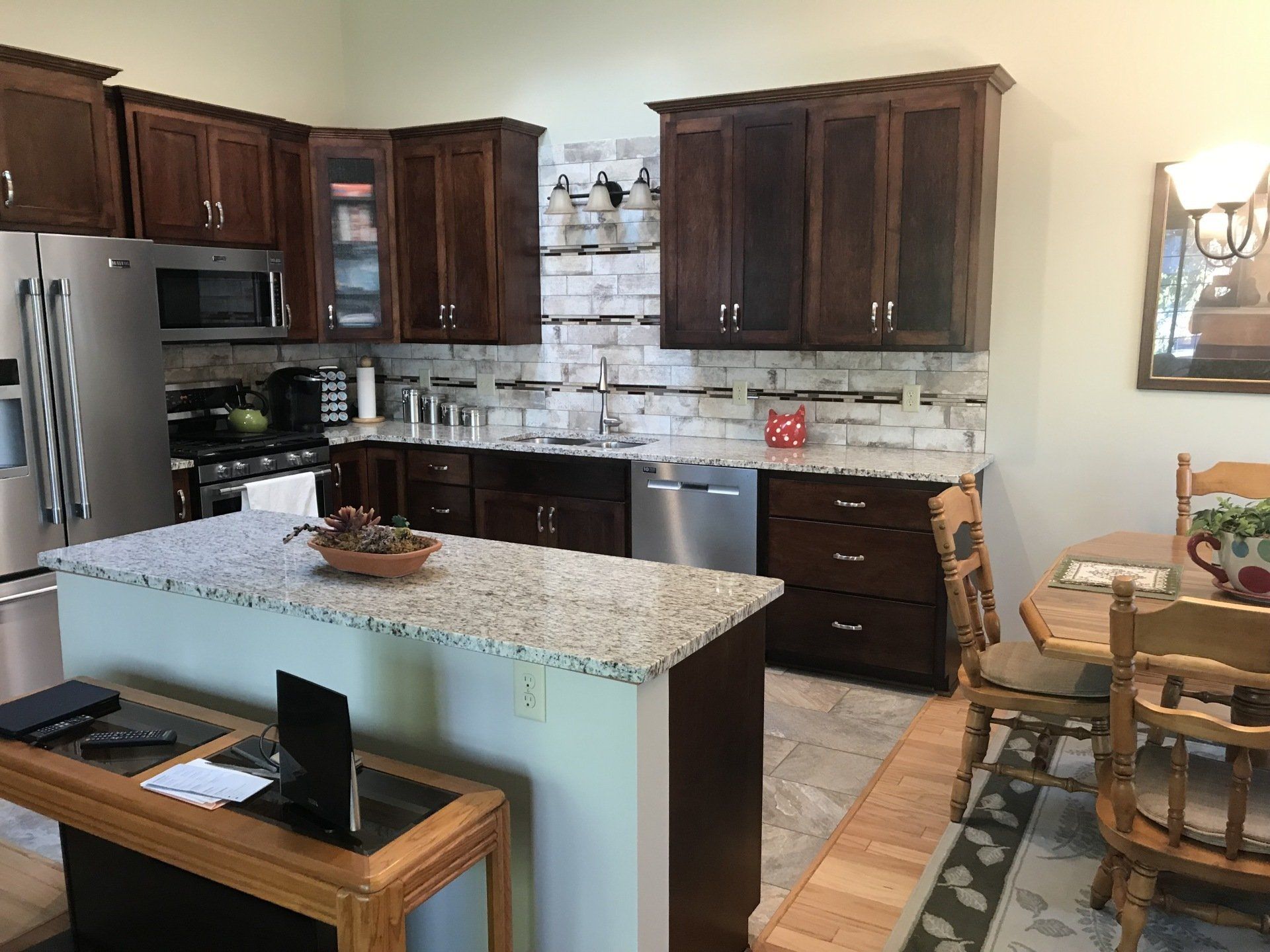 Kitchen with wood cabinets, stainless steel appliances, granite island, and dining area.